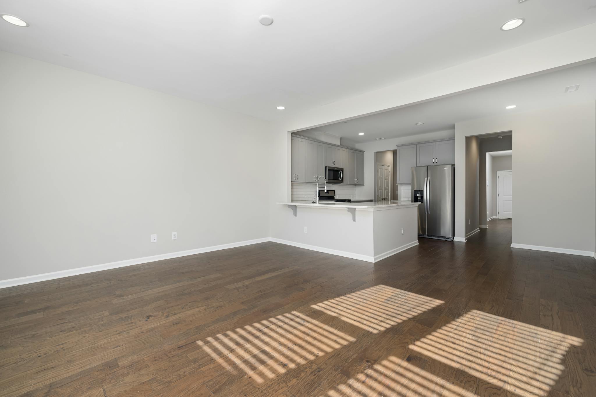 Spacious empty apartment featuring modern kitchen and hardwood floors.
